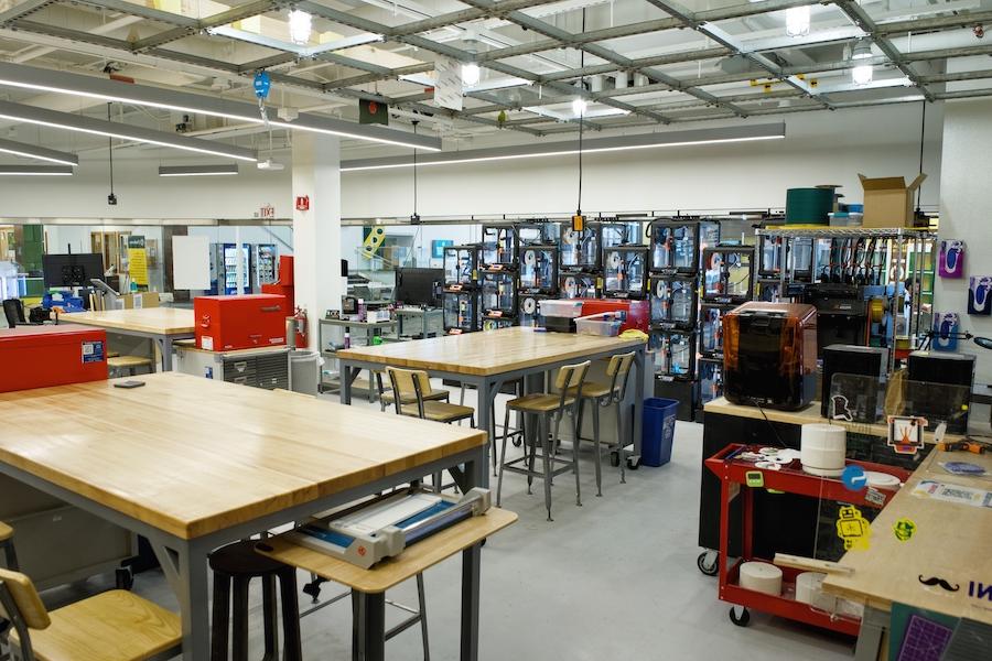 A room filled with 3D printers, large tables, hand tools, and other physical creation equipment.