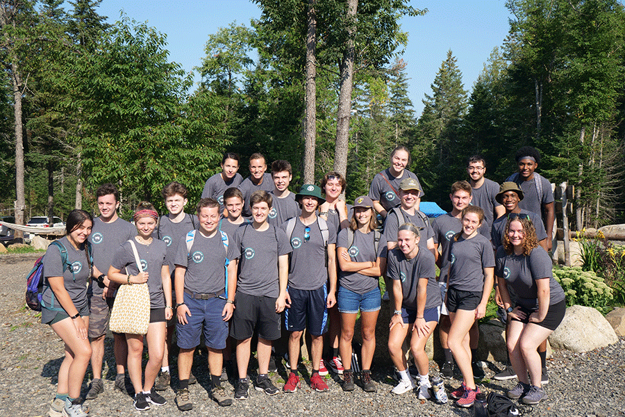 A group of Clarkson Ignite students post outside for a photo all wearing matching grey t-shirts with trees in the background